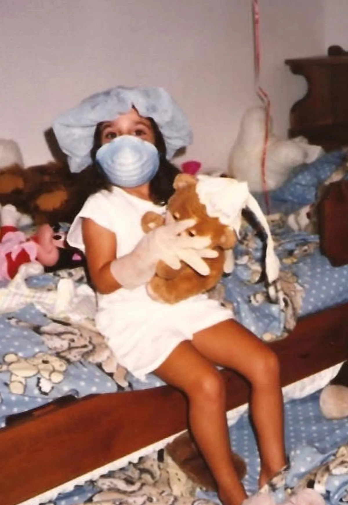 Dr. Heagy as a girl, wearing a surgical mask and examining a teddy bear